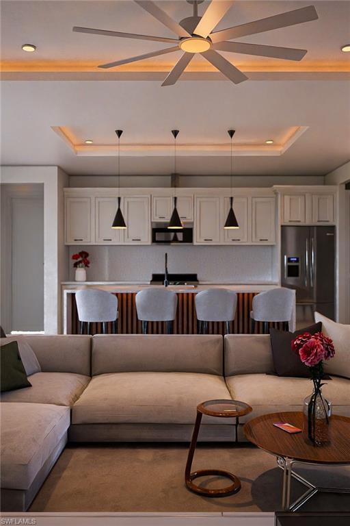Open-concept living area with a large ceiling fan, recessed lighting, and a tray ceiling