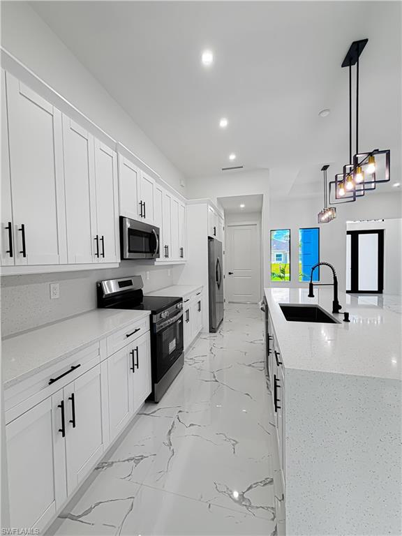 Modern kitchen featuring white shaker cabinetry with matte black hardware, stainless steel appliances, and light-toned countertops