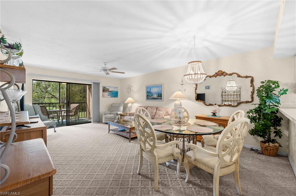 Open-concept living space featuring patterned carpet flooring, a ceiling fan, and a screened lanai with outdoor seating