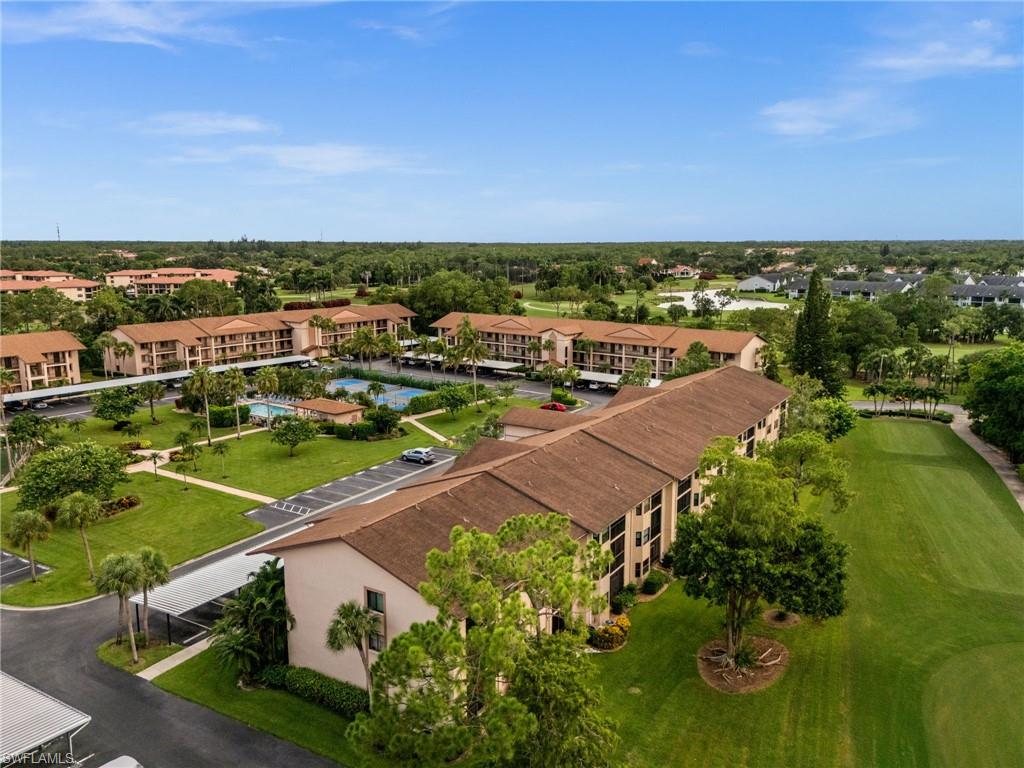 Aerial perspective showcasing multiple residential buildings with terracotta-style roofs, surrounded by extensive green spaces