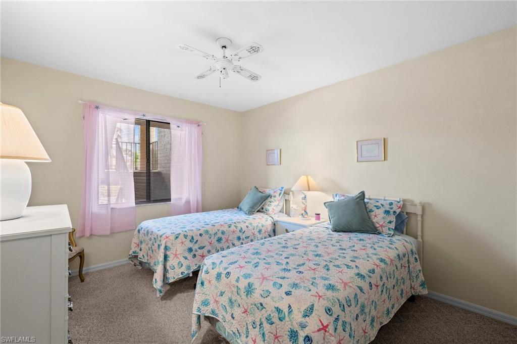 Carpeted room featuring a ceiling fan with light fixture, window with sheer pink curtains, and light neutral wall paint