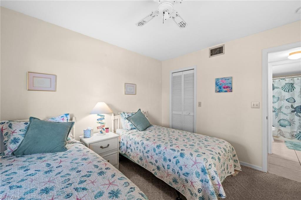 Bedroom featuring two single beds, carpet flooring, a white ceiling fan, and a bi-fold closet door