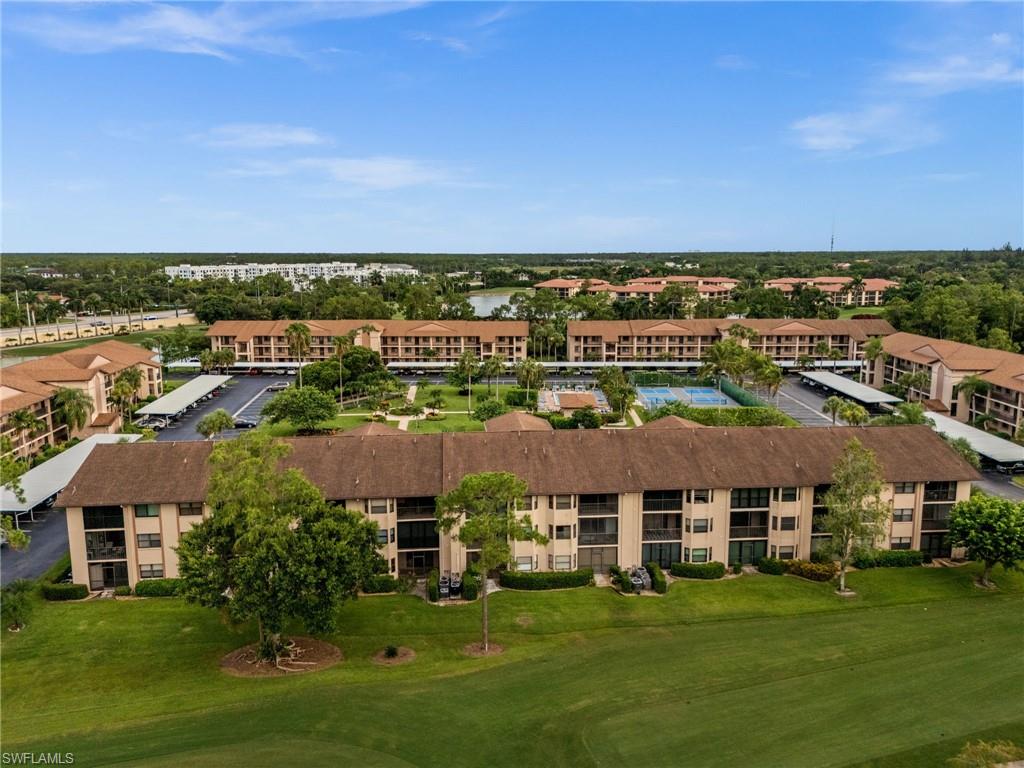 Community featuring multiple multi-story residential buildings, ample green spaces, and covered parking areas