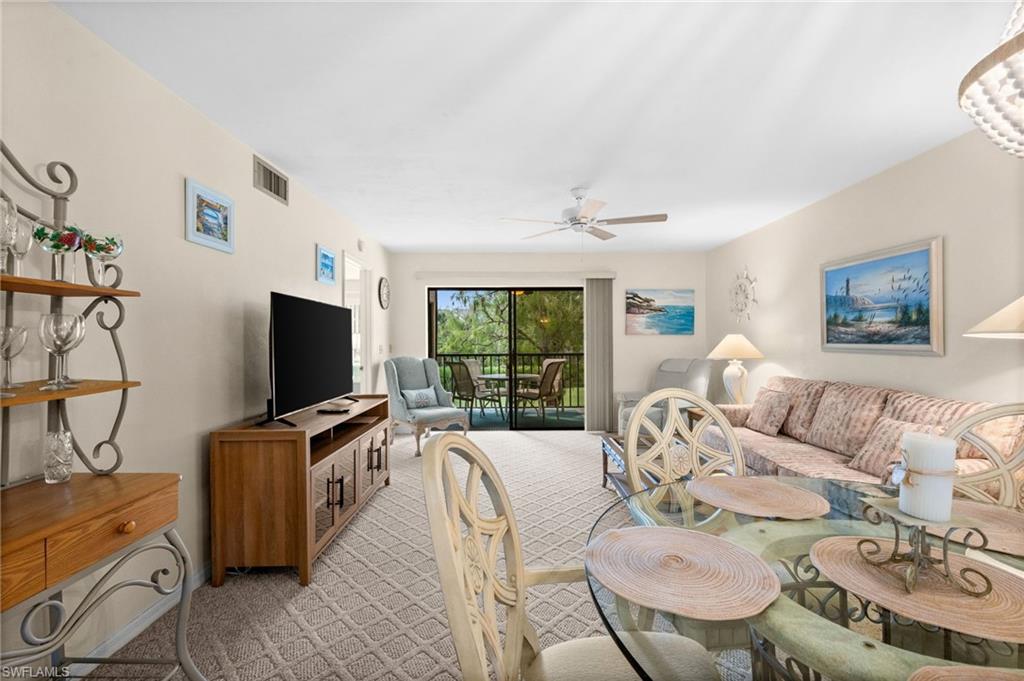 Open living and dining space, bright and comfortable, with sliders to the screened lanai and the golf course beyond.