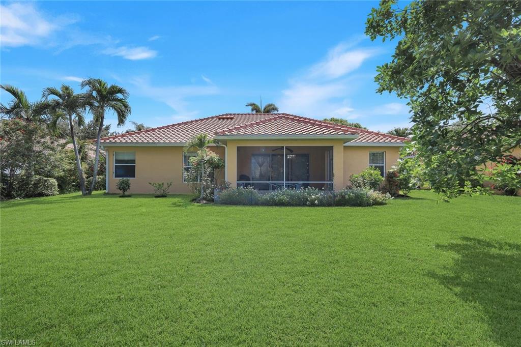 Expansive green lawn bordering a stucco exterior home with a tiled roof