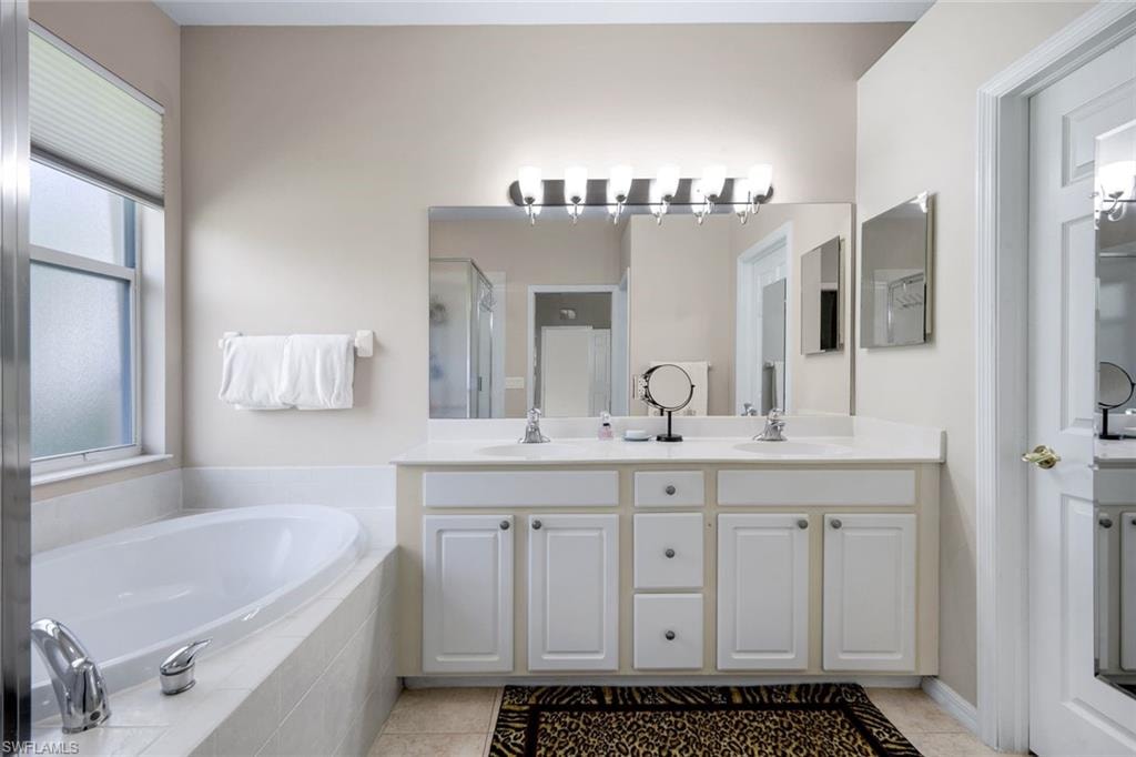 Dual vanity with white cabinetry and chrome hardware, featuring a large mirror and overhead multi-bulb lighting