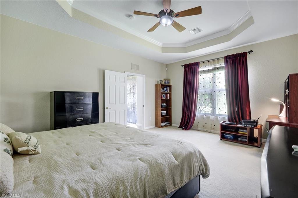 Spacious room featuring a tray ceiling with a ceiling fan, carpet flooring, and a large window