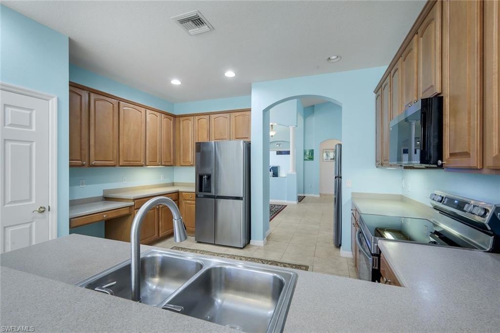 Kitchen featuring a double basin stainless steel sink with a high-arc faucet, ample cabinetry, and stainless steel appliances