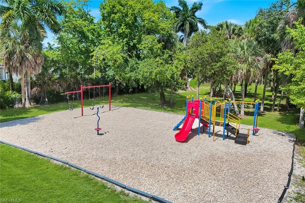 Outdoor play area featuring a swing set, multi-feature play structure with slides, and wood chip surfacing