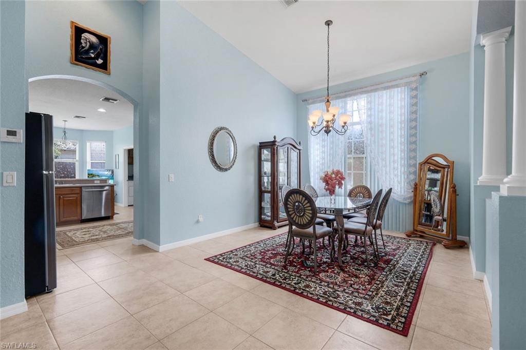 Dining area featuring high ceilings, light-toned tile flooring, and an arched entryway