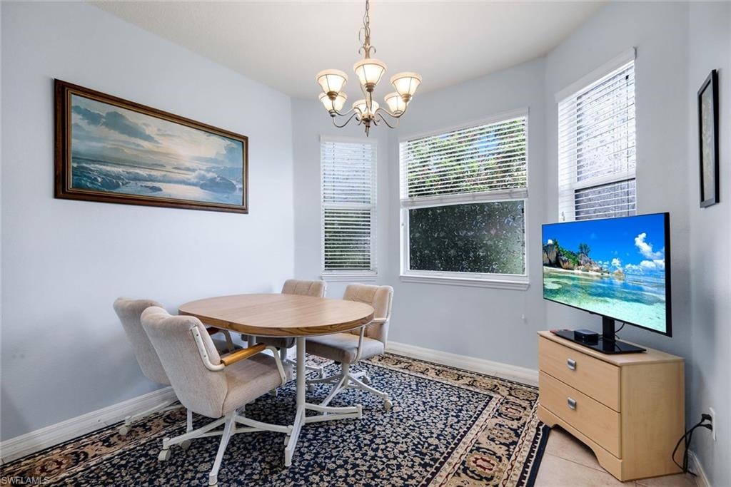 Dining area featuring a chandelier, multiple windows with blinds, light blue wall paint, and tile flooring