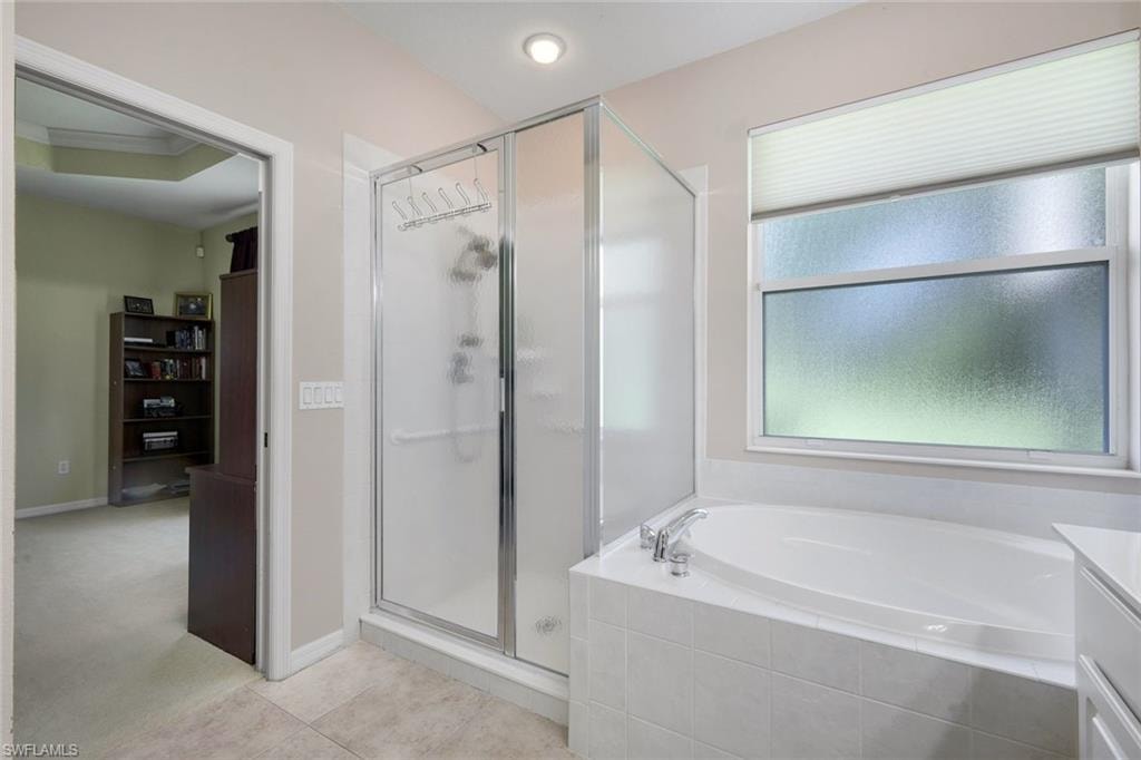 Bathroom featuring a glass-enclosed shower, a built-in soaking tub with tiled surround, and a frosted privacy window with a cellular shade