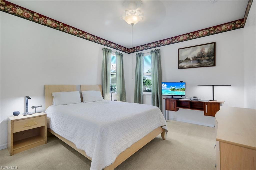 Carpeted room featuring dual windows with blinds, a ceiling-mounted light fixture, and a decorative floral border