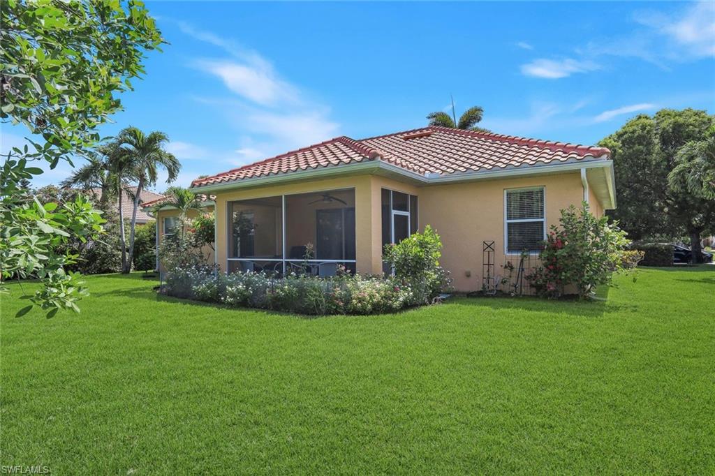 Mediterranean-style exterior featuring a terra cotta tile roof, a screened patio, and a light stucco finish