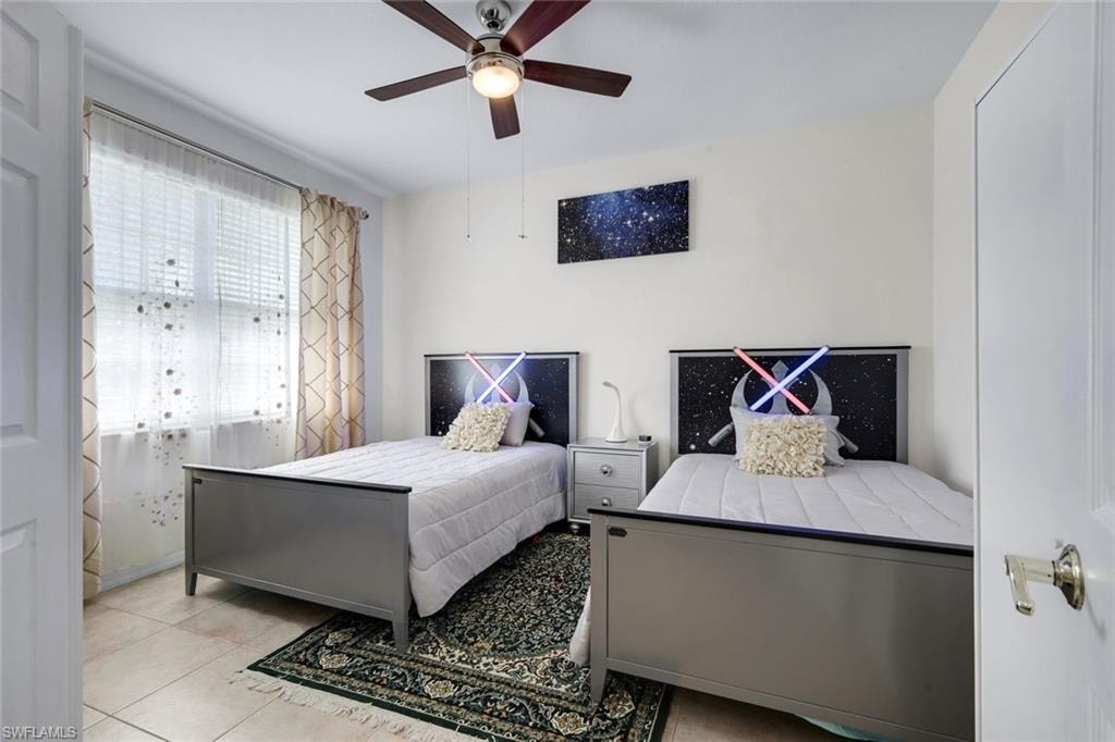 Spacious room featuring tile flooring, a window with horizontal blinds and decorative sheer curtains, a ceiling fan with integrated lighting, and a neutral wall color