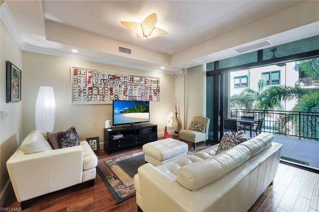Open-concept living area featuring wood-finish flooring, crown molding, and recessed lighting