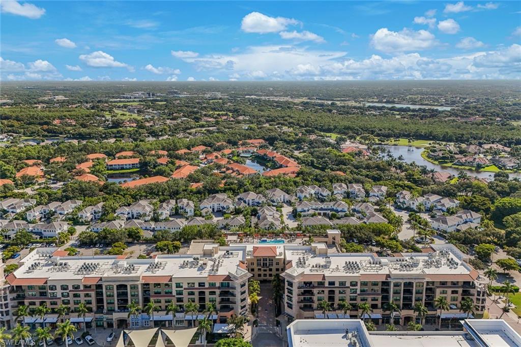 Expansive aerial perspective showcasing a multi-story building with a central courtyard, surrounded by residential properties and abundant mature trees