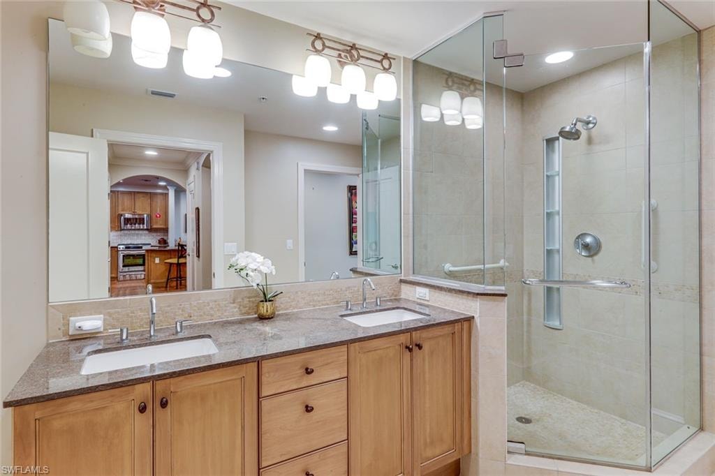 Bathroom featuring a double vanity with granite countertop, undermount sinks, and wood cabinetry