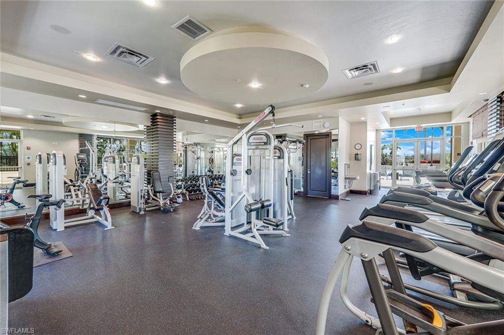 Spacious fitness center featuring rubber flooring, mirrored walls, recessed lighting, and large windows