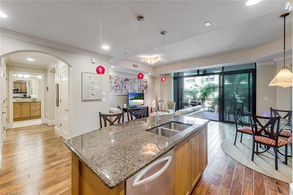 Kitchen island featuring a double-basin stainless steel sink, granite countertop, and light wood cabinetry
