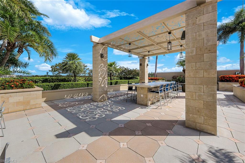 Outdoor entertaining area featuring a stone pergola with decorative metalwork and hanging lanterns