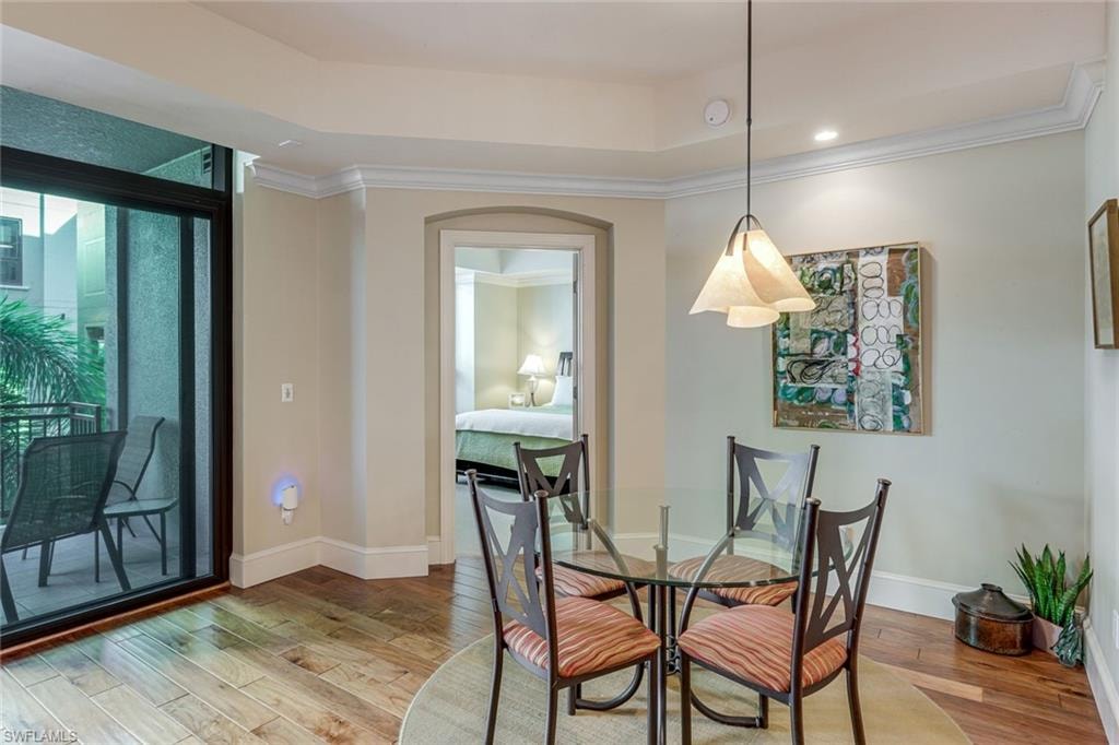 Dining area featuring wood-finish flooring, crown molding, and a tray ceiling