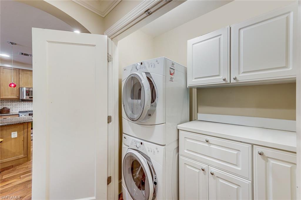 Dedicated laundry area featuring stacked appliances and white cabinetry
