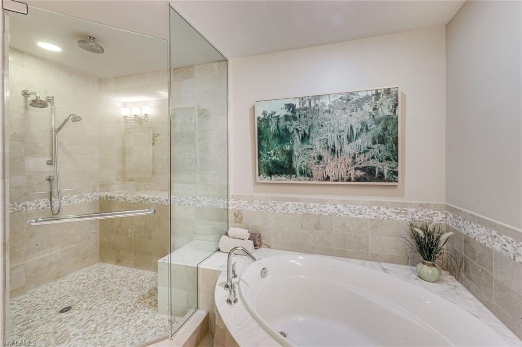 Tiled walk-in shower with glass enclosure, dual shower heads, and built-in bench seating