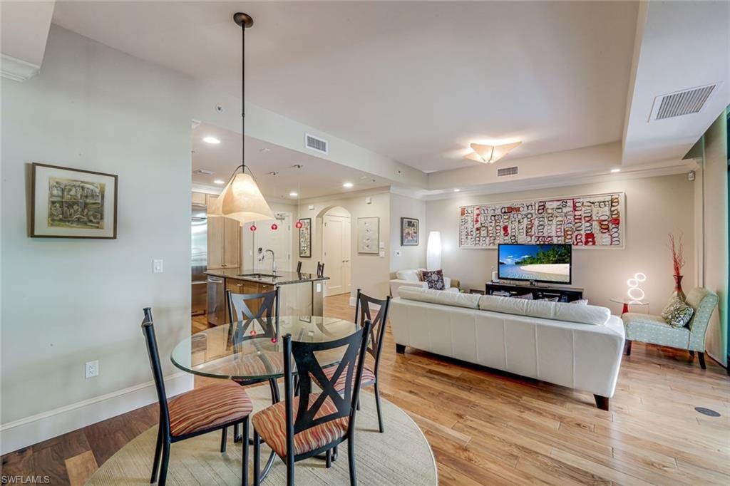 Open-concept living area featuring wood-finish flooring, recessed lighting, and crown molding
