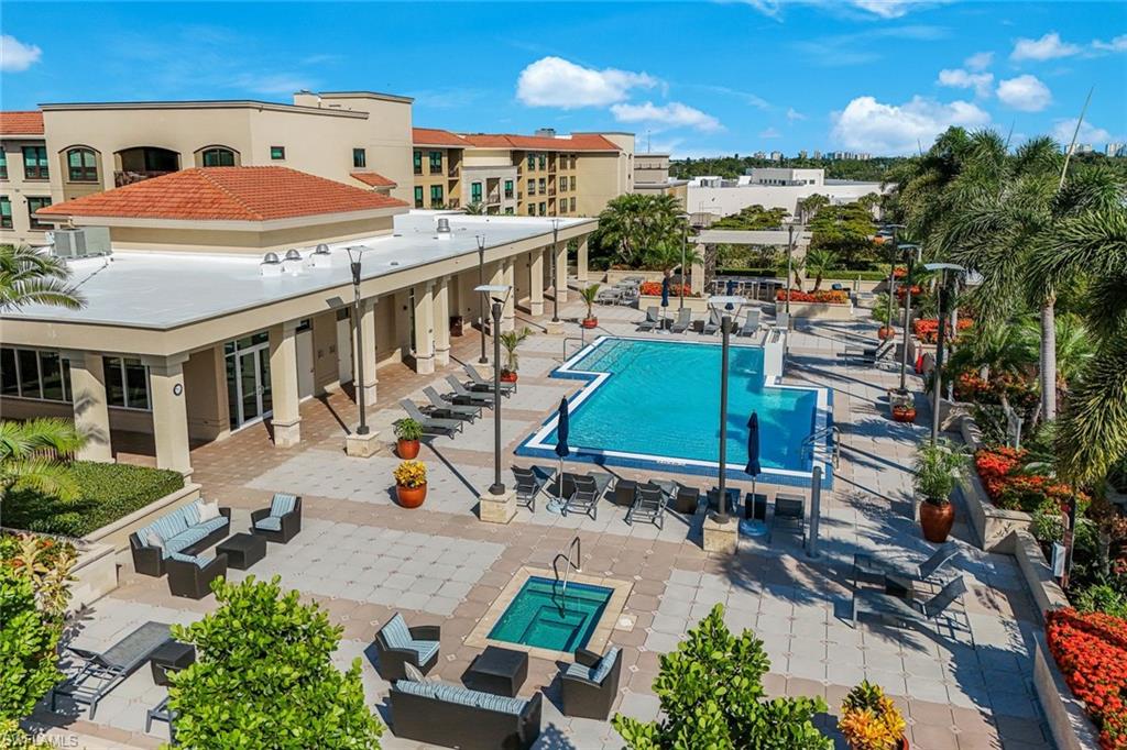 Expansive paver patio featuring a rectangular swimming pool, integrated spa, and surrounding lounge areas