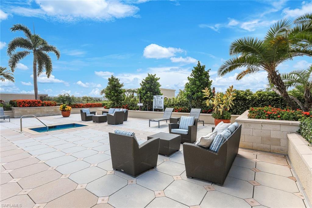 Spacious outdoor patio featuring patterned paver flooring, a sunken spa, and lush landscaping