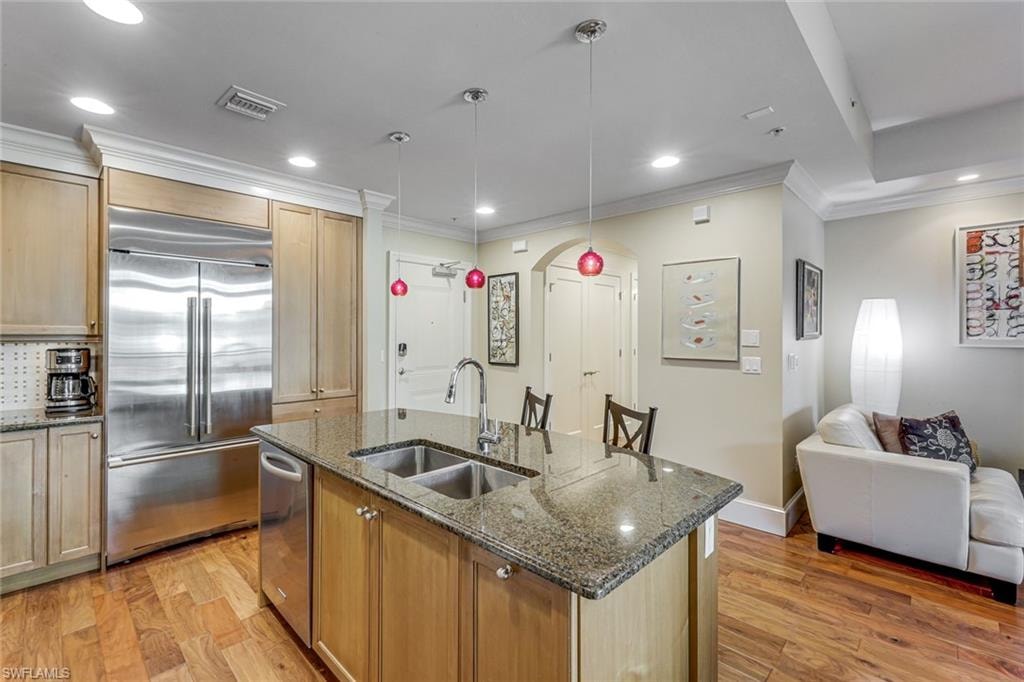 Kitchen island featuring a dual basin sink, granite countertop, and pendant lighting
