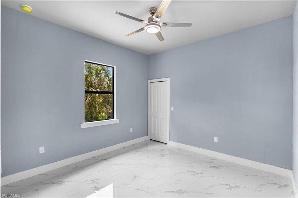 Room featuring light blue walls, white baseboards, and white tile flooring with grey veining