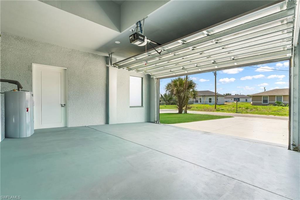 Spacious garage featuring a light grey epoxy floor, textured walls, and a panel door leading into the interior