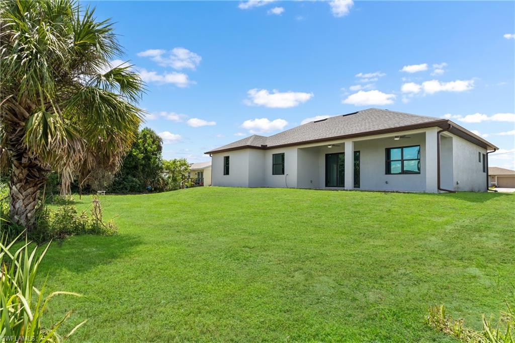Expansive green lawn with mature palm tree and a covered patio