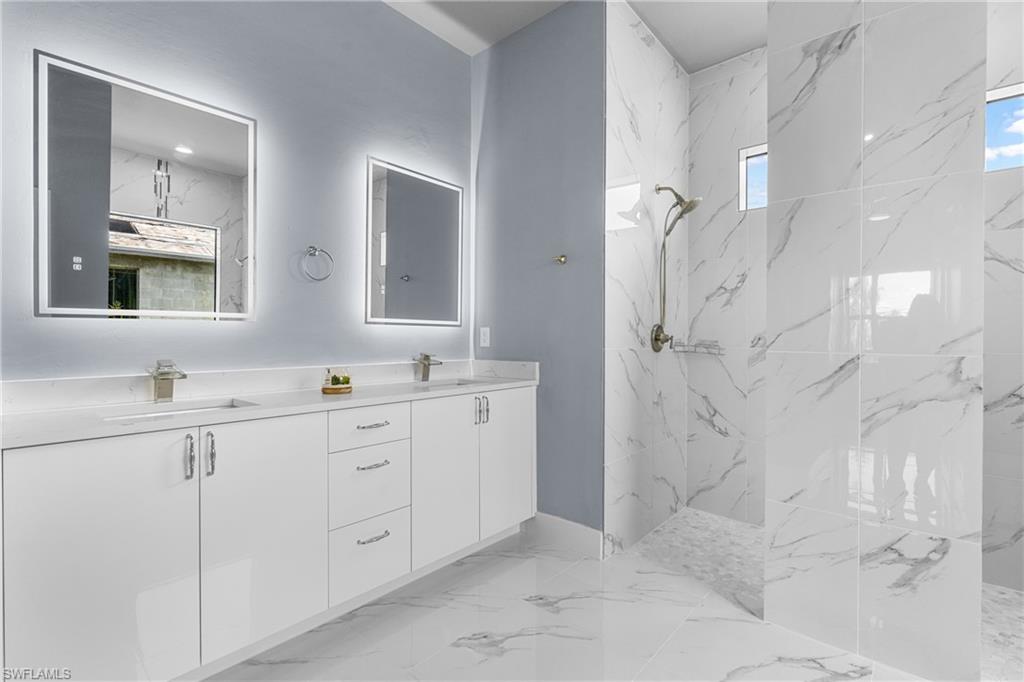 Dual vanity with white cabinetry and integrated sinks, illuminated by backlit mirrors