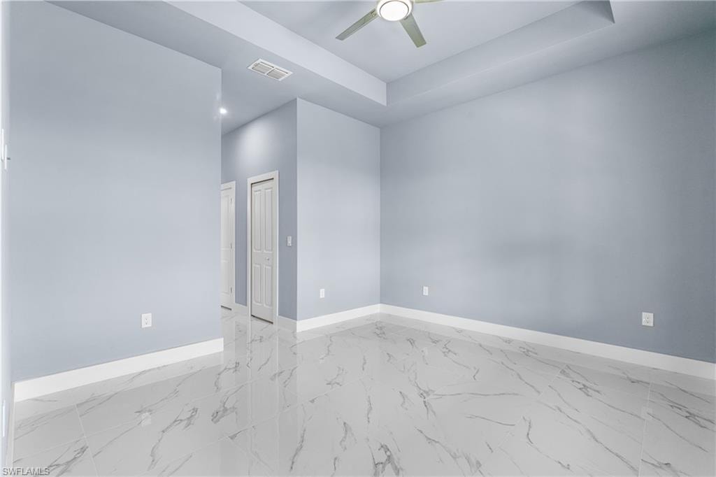 Spacious room featuring light blue walls, white baseboards, and polished porcelain tile flooring