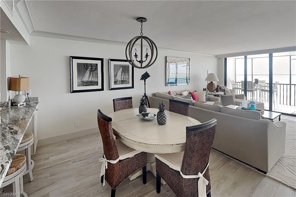 Open-concept living area featuring light wood-finish flooring, white walls, and crown molding