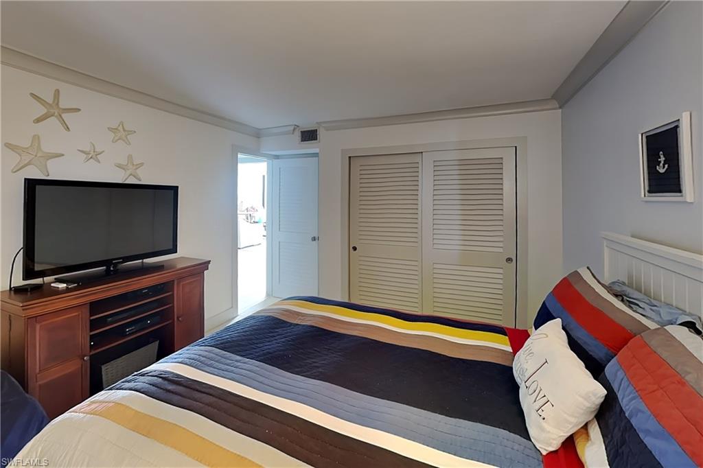 White walls with gray crown molding throughout, louvered bi-fold closet doors, and white paneled door