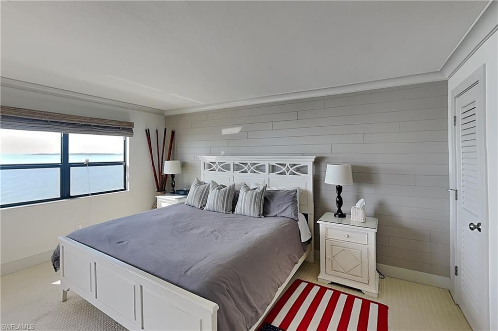 Bedroom featuring a large window with water scenery, horizontal wall paneling, and crown molding