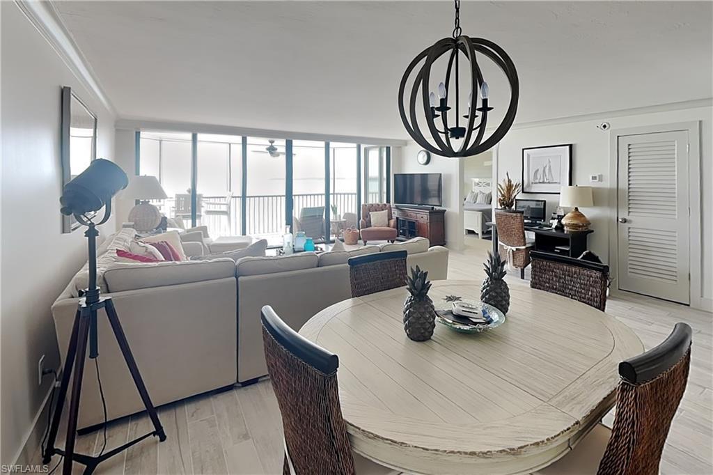 Open-concept living space featuring wood-finish flooring, a contemporary spherical chandelier, and expansive windows