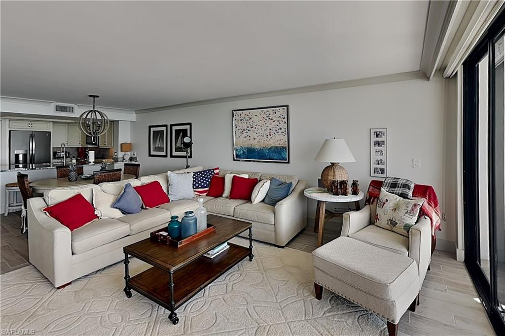 Open-concept living area with light-toned walls, wood-finish flooring, and a large area rug