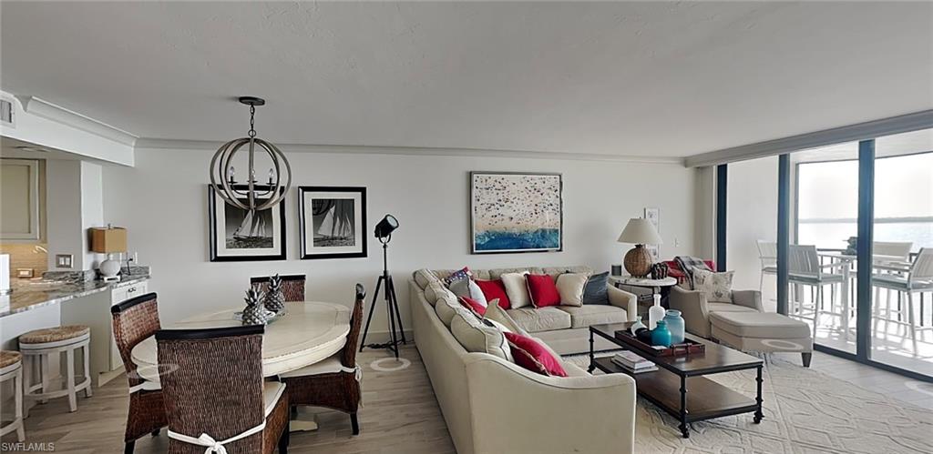Open-concept living area featuring a dining space with an orb chandelier, a living room, and expansive sliding glass doors