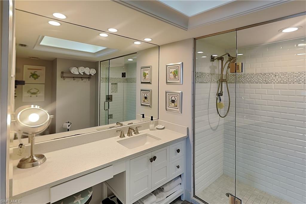 Contemporary bathroom featuring a glass-enclosed shower with white subway tile, a vanity with a light-toned countertop, integrated sink, and brushed nickel fixtures