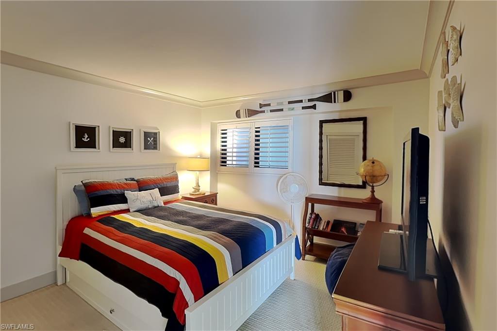 Bedroom featuring a window with white louvered shutters, crown molding, and a light-toned carpet flooring