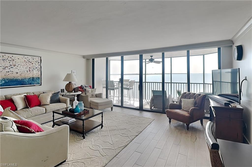 Expansive living area featuring light wood-finish flooring and a private balcony overlooking water