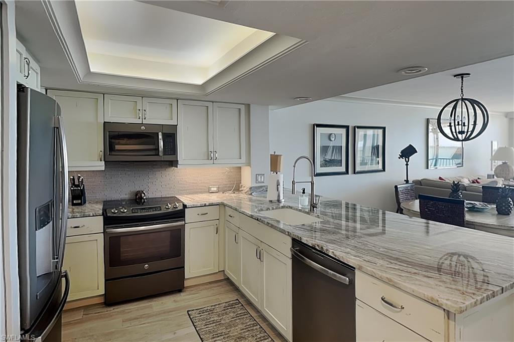 Modern kitchen featuring light-toned cabinetry, a stainless-steel refrigerator, and a built-in microwave