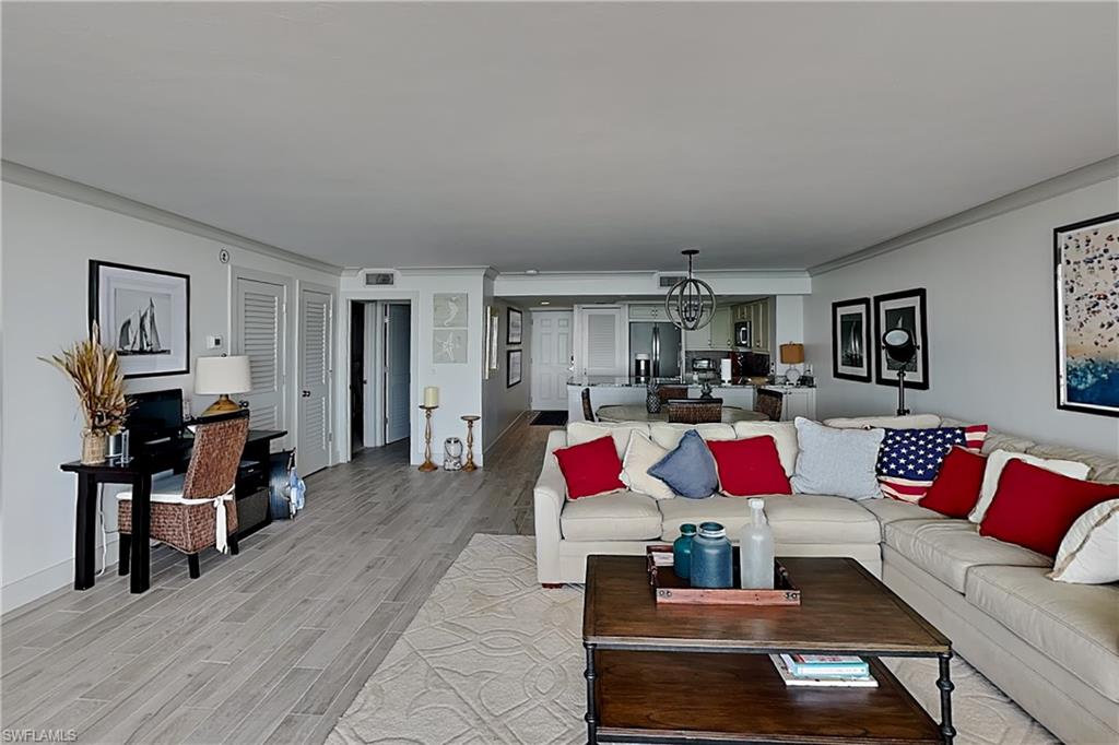 Open-concept living area featuring wood-finish plank flooring, crown molding, and recessed lighting