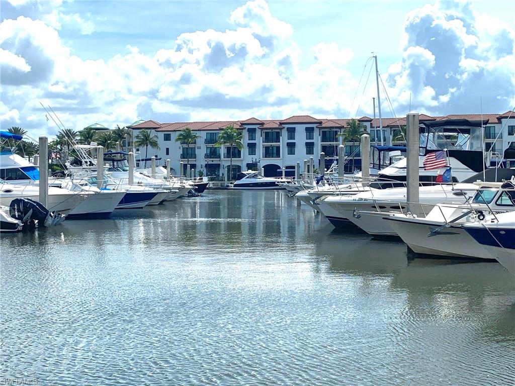 Waterfront property featuring a private marina with multiple boat slips, white stucco exterior, and red tile roofing