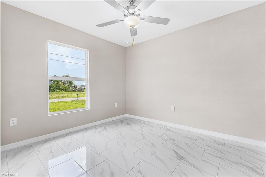 Light-filled room featuring large format tile flooring, a white window frame, and a ceiling fan with integrated lighting